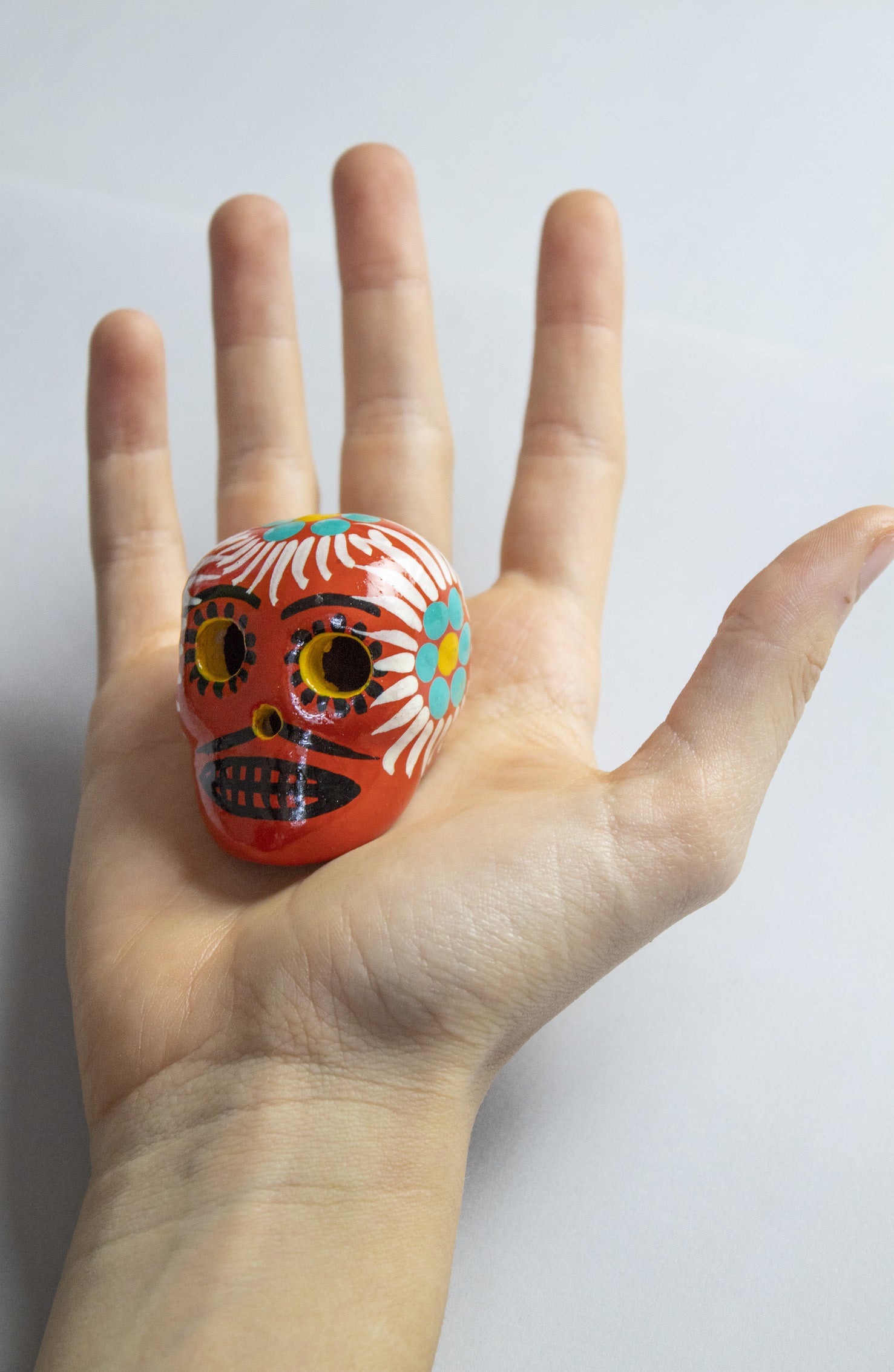 Teschio calavera rosso mattone con decorazioni floreali fatte a mano